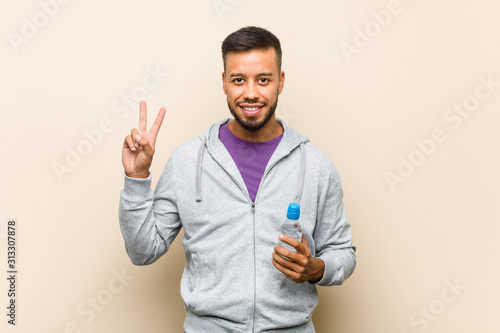 Young mixed race asian man holding a water bottle showing number two with fingers. © Asier