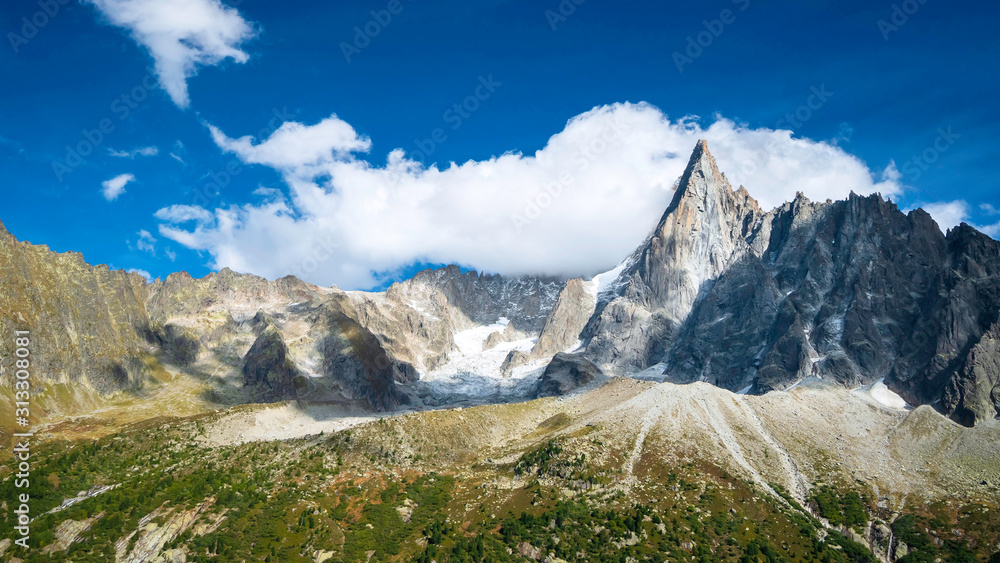 Alpine landscape on a sunny summer day. Rocky mountains against the blue sky with beautiful clouds.