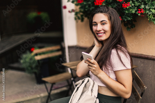 Beautiful woman using phone sitting in street cafe.