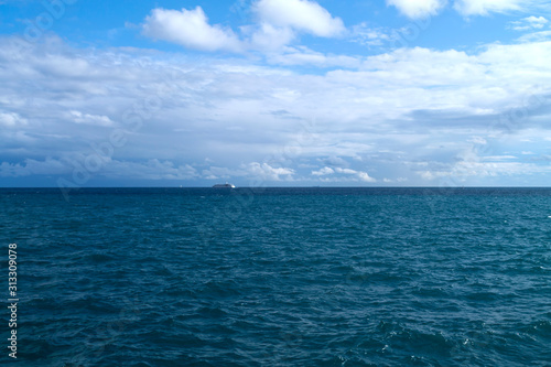 Blue sea, cloudy sky and ships on horizon