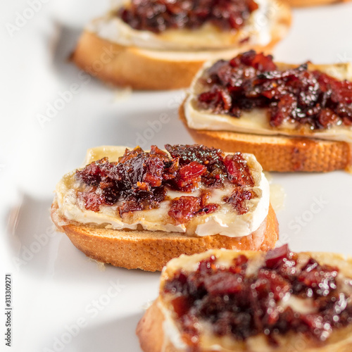 Bacon Jam and Brie Crostini Appetizer on a White Plate