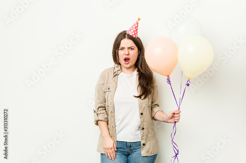Young plus size curvy woman celebrating a birthday screaming very angry and aggressive.
