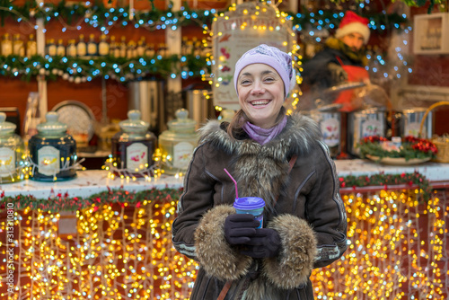 Beautiful young woman with coffee cup in the city. Beautiful woman with coffee on the street in winter clothes. Woman Having Hot Drink Outdoors On Winter Market