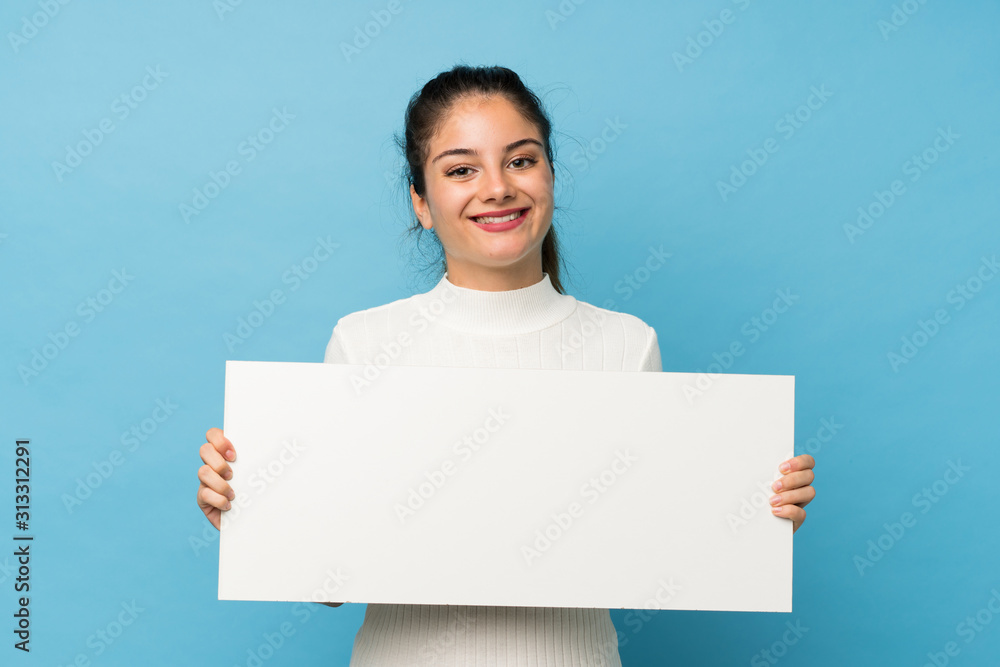 Young brunette girl over isolated blue background holding an empty white placard for insert a concept Young brunette girl over isolated blue background holding an empty white placard for insert a concept