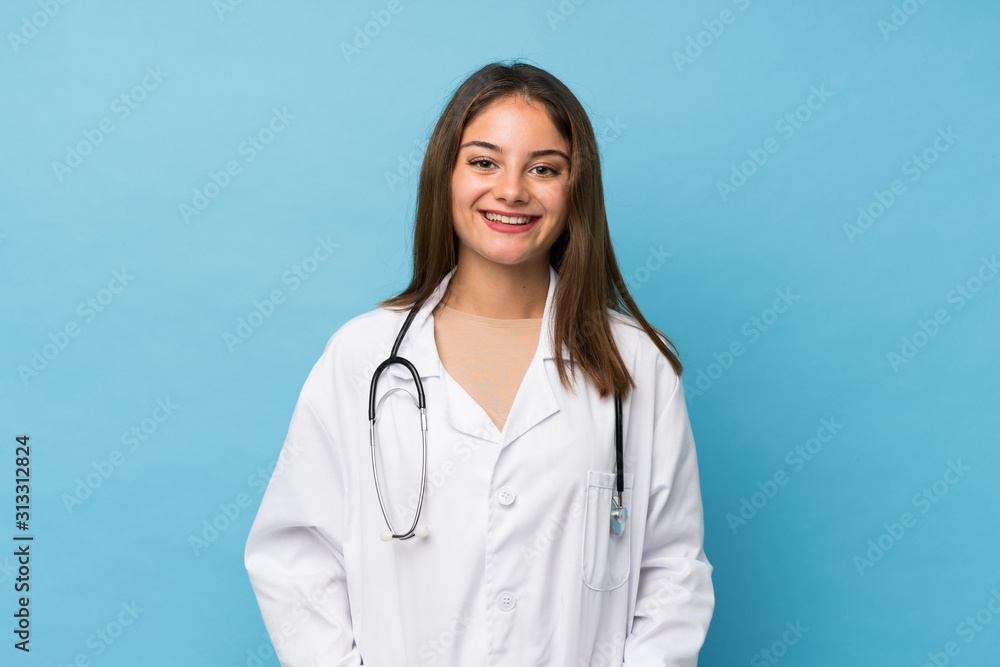 Young brunette girl over isolated blue background with doctor gown Young brunette girl over isolated blue background with doctor gown