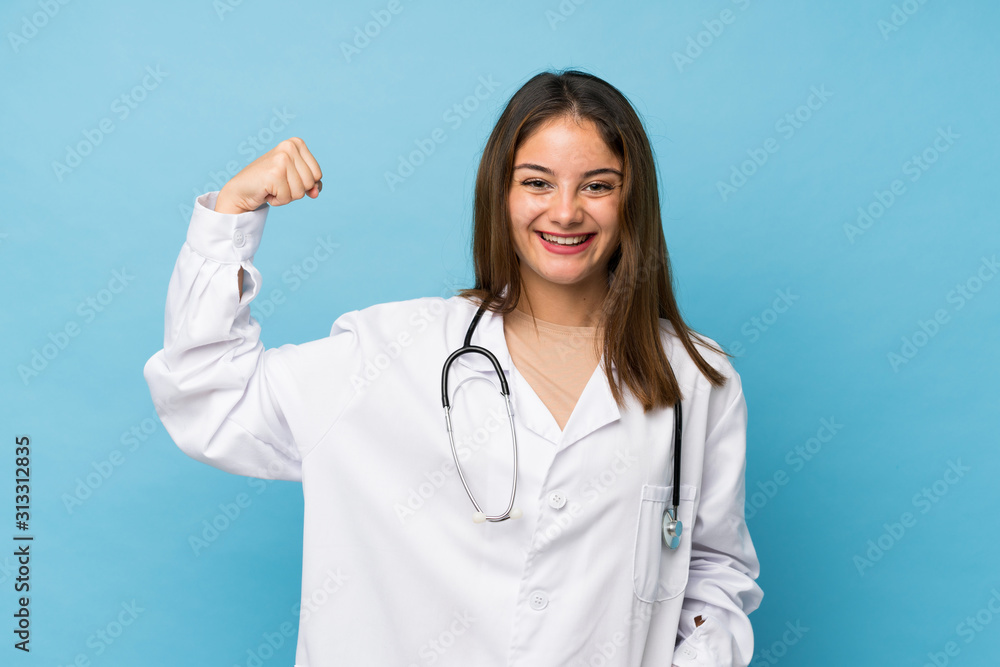 Young brunette girl over isolated blue background with doctor gown and making strong gesture Young brunette girl over isolated blue background with doctor gown and making strong gesture