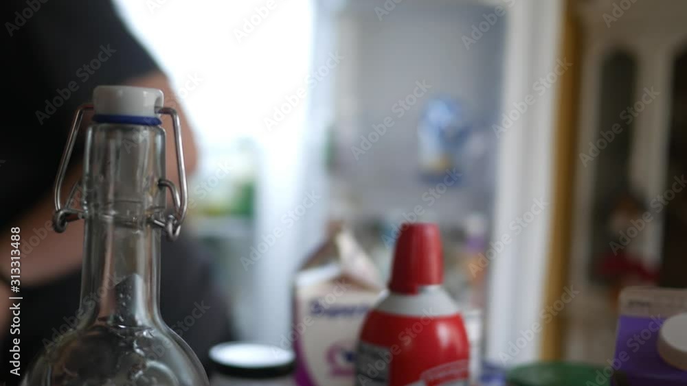 A defocused woman dances happily while cleaning out her cluttered fridge A defocused woman dances happily while cleaning out her cluttered fridge
