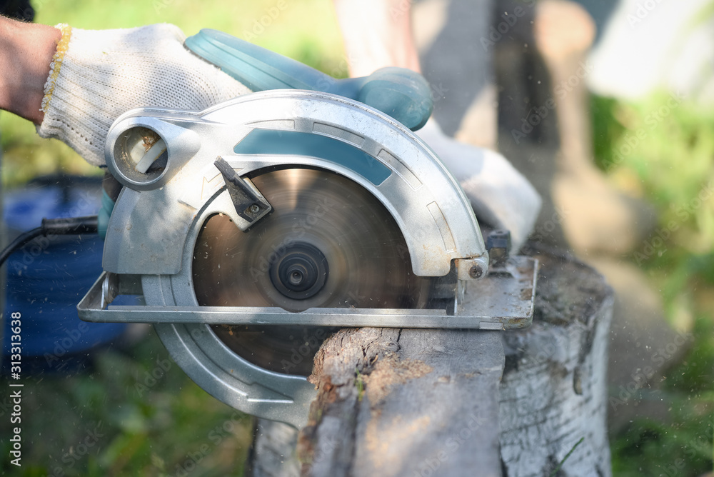 Carpenter is sawing a wooden plank by a circular saw close up. Carpenter is sawing a wooden plank by a circular saw close up.