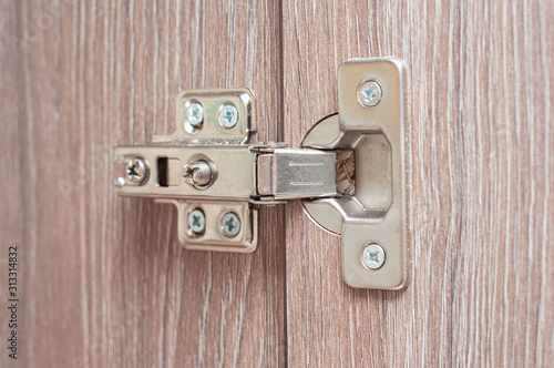 The hinge of the kitchen hinged bedside table that holds the wooden door. Kitchen fittings and their installation.