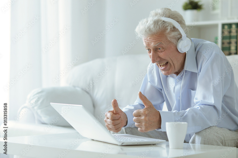 Emotional senior man using laptop at home Emotional senior man using laptop at home
