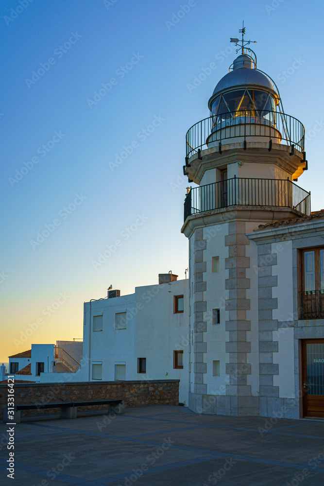 white lighthouse at sunset in the medieval and mediterranean town of Peniscola, Spain.