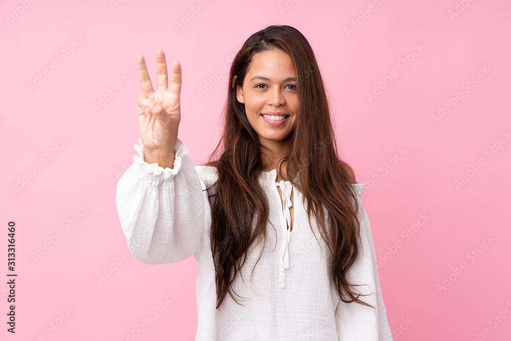 Young Brazilian girl over isolated pink background happy and counting three with fingers Young Brazilian girl over isolated pink background happy and counting three with fingers