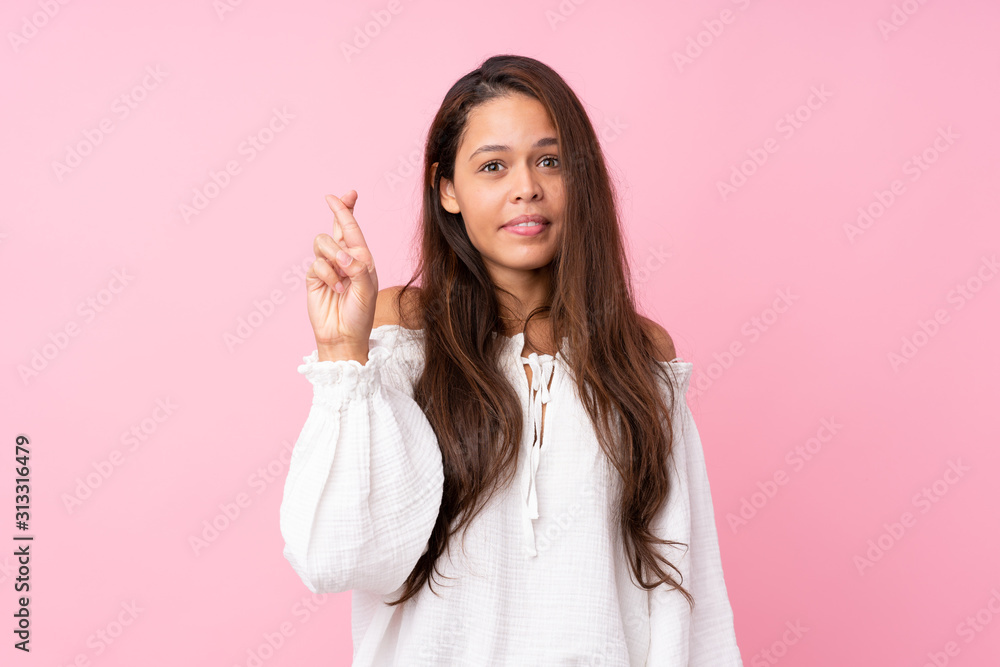 Young Brazilian girl over isolated pink background with fingers crossing and wishing the best Young Brazilian girl over isolated pink background with fingers crossing and wishing the best