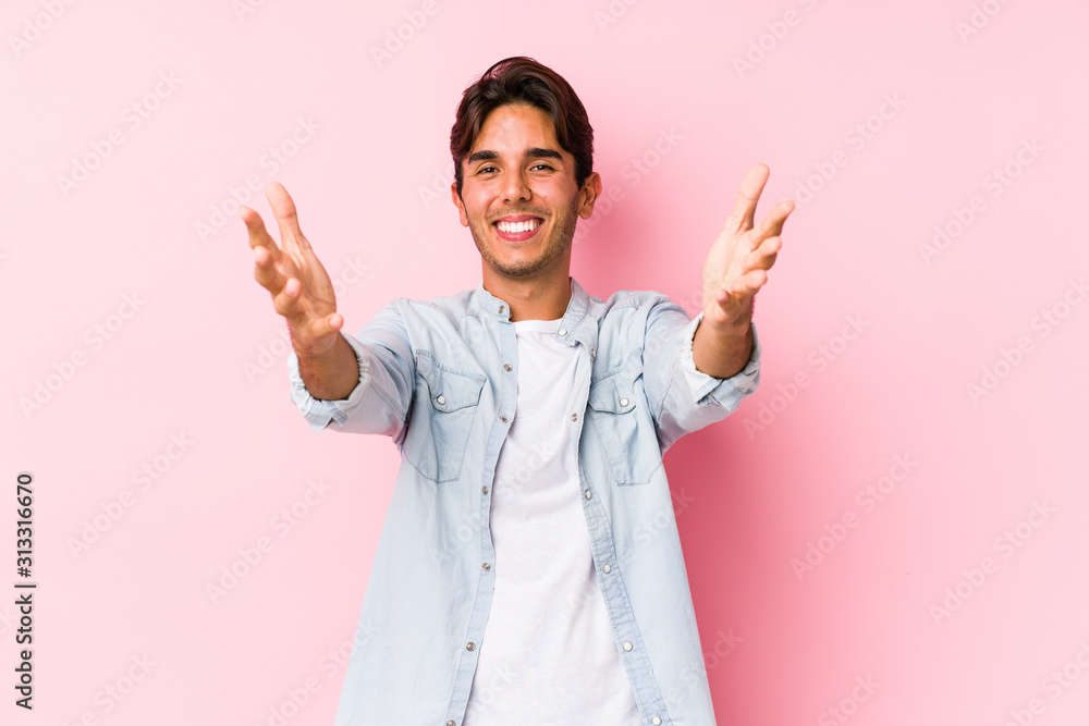 Young caucasian man posing in a pink background isolated feels confident giving a hug to the camera. Young caucasian man posing in a pink background isolated feels confident giving a hug to the camera.