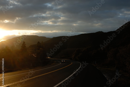 Cars traveling through a mountainous section of highway at dusk.