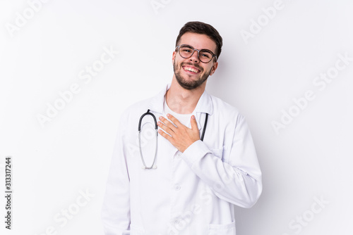Young caucasian doctor man isolated laughs out loudly keeping hand on chest.