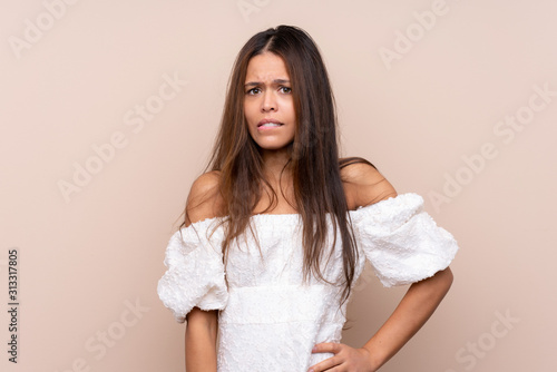 Young Brazilian girl over isolated background having doubts and with confuse face expression