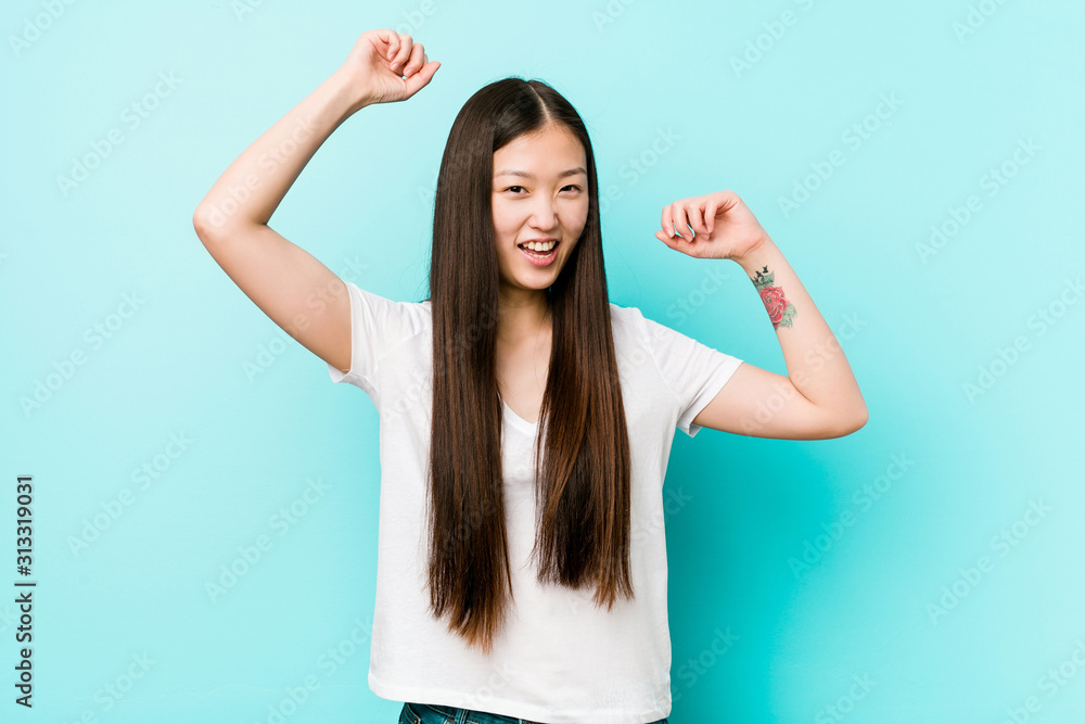 Young pretty chinese woman celebrating a special day, jumps and raise arms with energy. Young pretty chinese woman celebrating a special day, jumps and raise arms with energy.