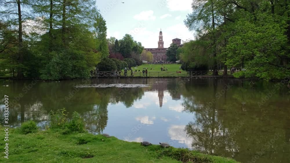 Milan, Italy - April, 2019 - Wide shot of Simplon Park (Parco Sempione) with a duck in the foreground and Sforza Castle (Castello Sforzesco) in the background. Milan, Italy - April, 2019 - Wide shot of Simplon Park (Parco Sempione) with a duck in the foreground and Sforza Castle (Castello Sforzesco) in the background.