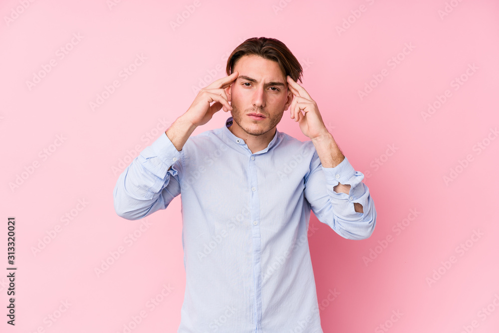 Young caucasian man posing in a pink background isolated focused on a task, keeping forefingers pointing head. Young caucasian man posing in a pink background isolated focused on a task, keeping forefingers pointing head.