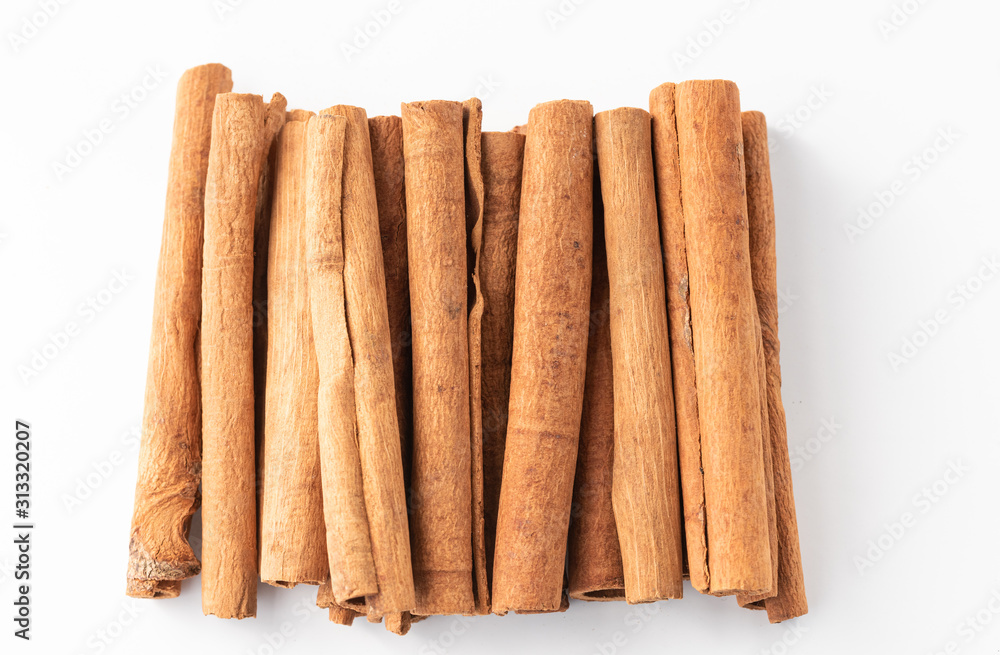 Cinnamon sticks lined up in a row on white background. Cinnamon sticks lined up in a row on white background.