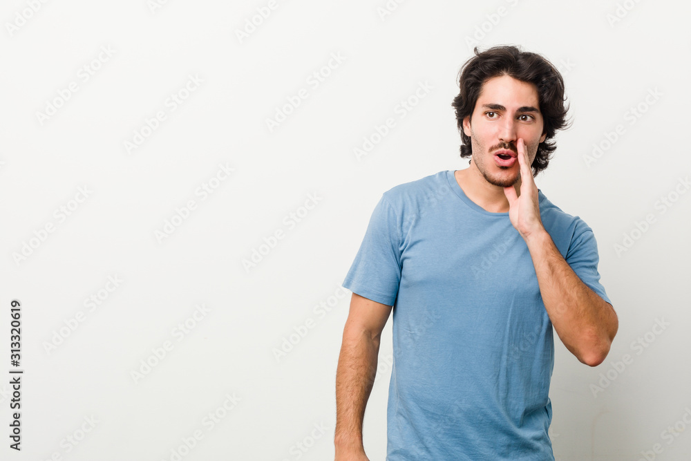 Young handsome man against a white background is saying a secret hot braking news and looking aside Young handsome man against a white background is saying a secret hot braking news and looking aside