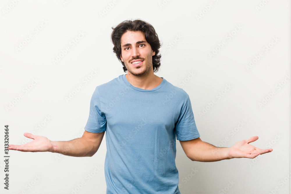 Young handsome man against a white background showing a welcome expression. Young handsome man against a white background showing a welcome expression.