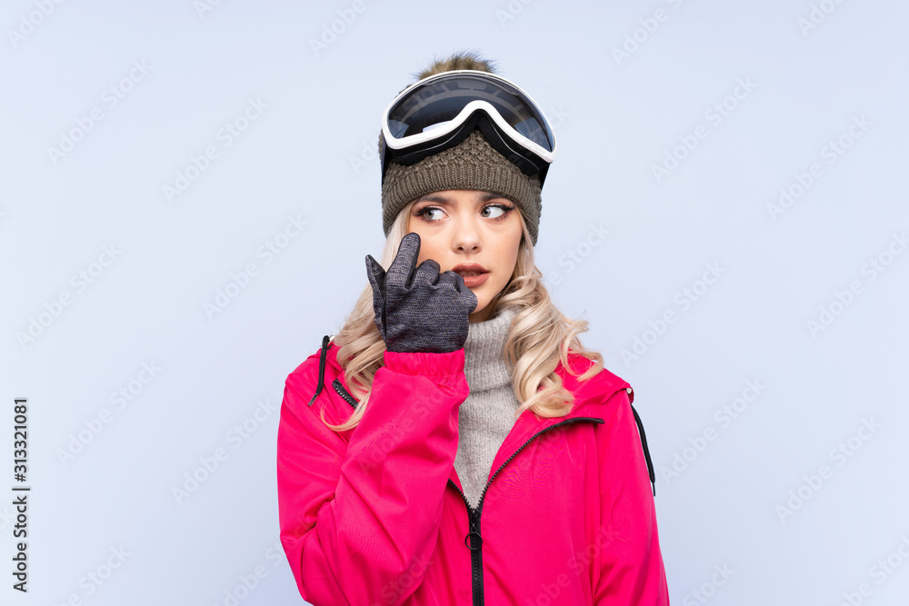 Skier teenager girl with snowboarding glasses over isolated blue background nervous and scared Skier teenager girl with snowboarding glasses over isolated blue background nervous and scared