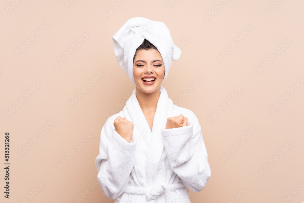 Teenager girl in a bathrobe over isolated background celebrating a victory Teenager girl in a bathrobe over isolated background celebrating a victory