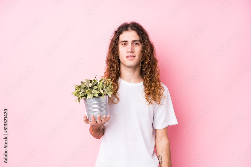 Long hair caucasian man holding a plant happy, smiling and cheerful. Long hair caucasian man holding a plant happy, smiling and cheerful.