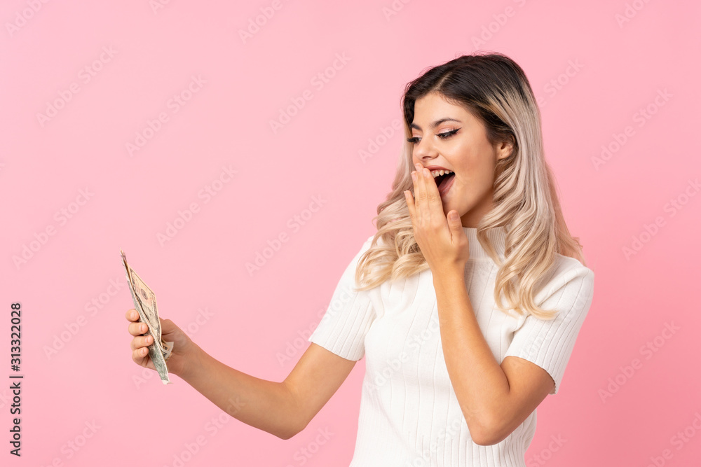 Teenager girl over isolated pink background taking a lot of money Teenager girl over isolated pink background taking a lot of money