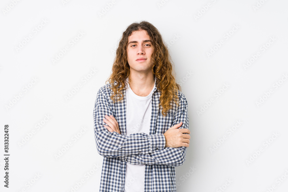 Young long hair man posing isolated who feels confident, crossing arms with determination. Young long hair man posing isolated who feels confident, crossing arms with determination.