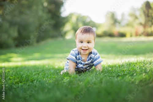 7 month child crawls on on green grass city park sunset outdoor. Concept education of children, activity outdoor. children's goods. Naked legs. Healthy baby. Happy childhood and baby healthcare.