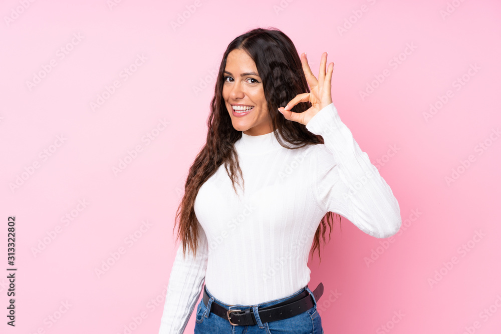 Young woman over isolated pink background showing ok sign with fingers Young woman over isolated pink background showing ok sign with fingers