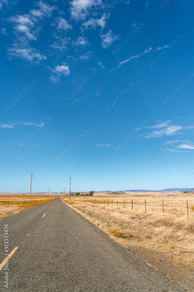 Portrait View of Two Lane Road Crossing Large Open Farm Lands