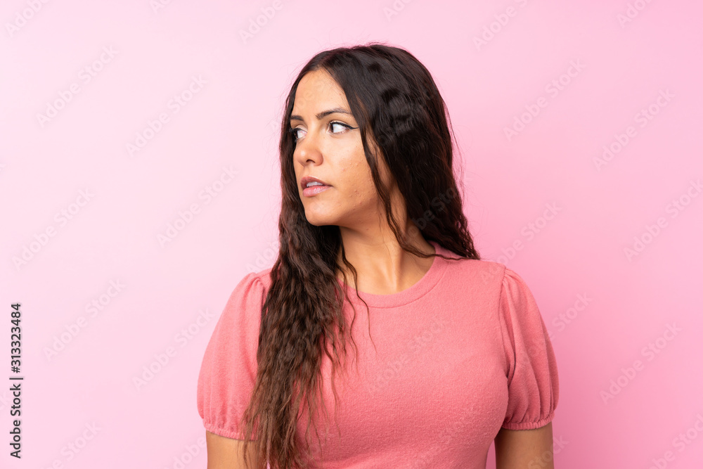 Young woman over isolated pink background looking side Young woman over isolated pink background looking side