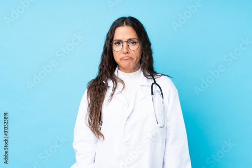 Billede på lærred Young doctor woman over isolated blue background sad