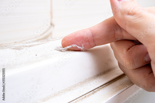 A hand taking a piece of dust from furniture, dusty home house concept