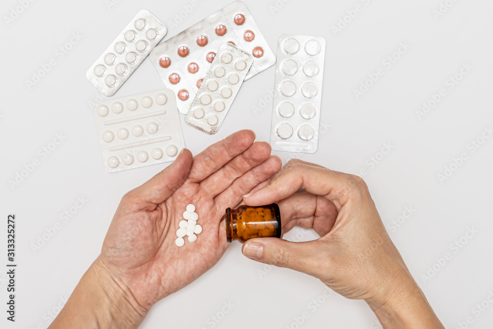 Obraz premium Hands holding a glass bottle and pills on a palm, patient taking pills and following doctor prescription