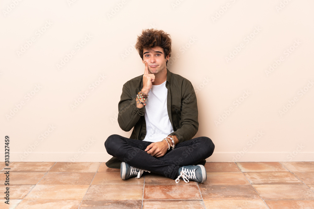 Young caucasian man sitting on the floor Looking front Young caucasian man sitting on the floor Looking front