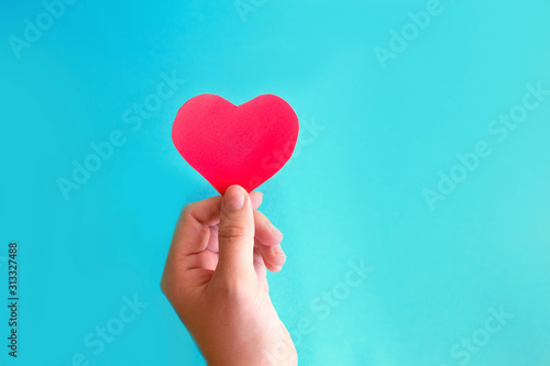 Hand holds heart on a blue background. Social media likes concept for valentines day.