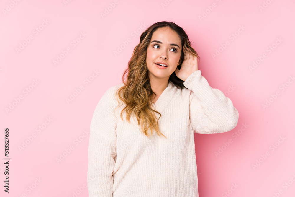 Young curvy woman posing in a pink background isolated trying to listening a gossip. Young curvy woman posing in a pink background isolated trying to listening a gossip.