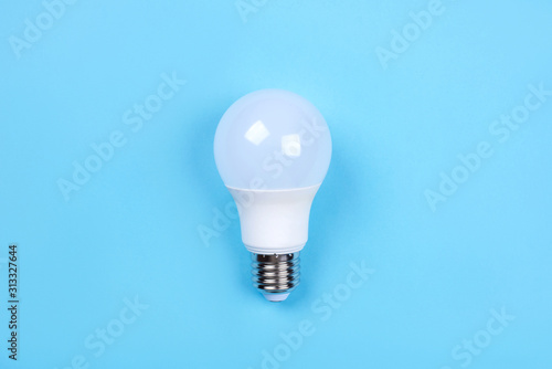 LED bulb on blue background. Saving energy concept. Ftat lay. Top view.