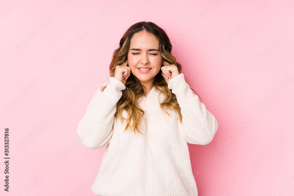 Young curvy woman posing in a pink background isolated covering ears with hands. Young curvy woman posing in a pink background isolated covering ears with hands.