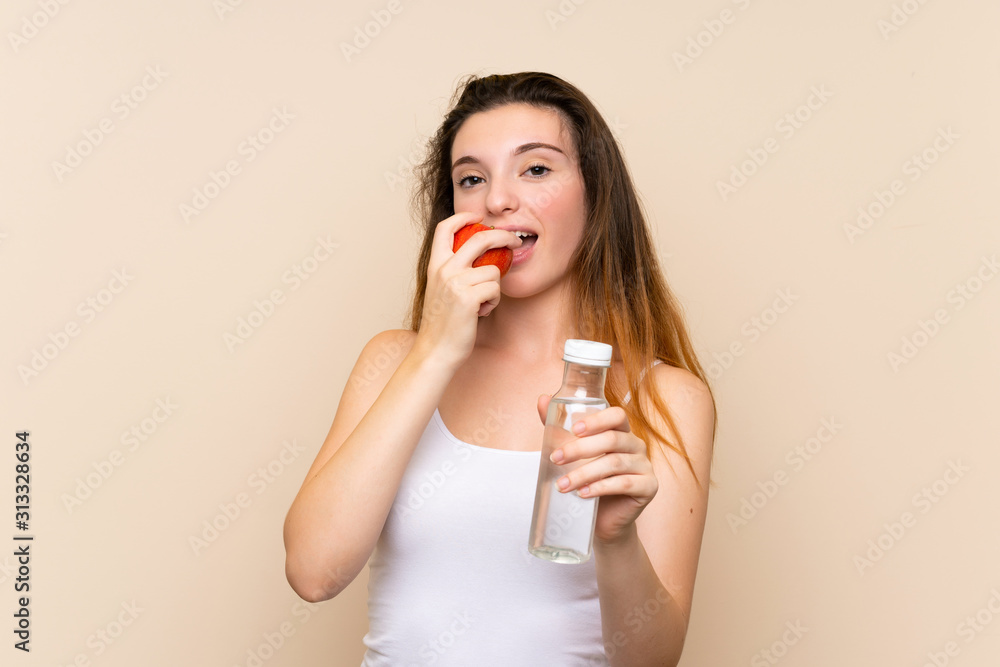 Young brunette girl with an apple and with a bottle of water over isolated background Young brunette girl with an apple and with a bottle of water over isolated background