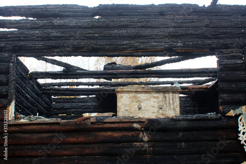 Country wooden house after a fire. Burnt walls, charred logs. The devastating effects of a fire.