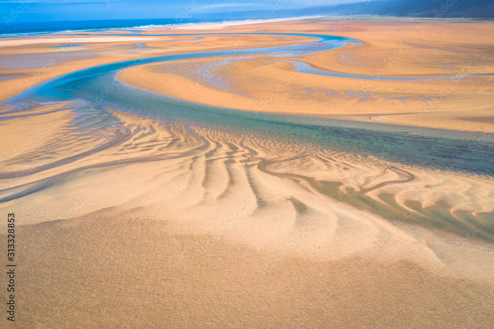 Aerial drone view of icelandic Raudasandur beach with azure water streams and yellow sand