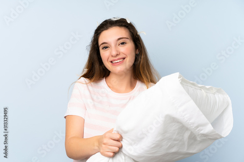 Young woman in pajamas over isolated blue background with happy expression