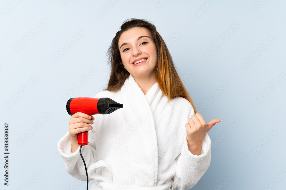 Young woman in a bathrobe with hair hairdryer pointing to the side to present a product Young woman in a bathrobe with hair hairdryer pointing to the side to present a product