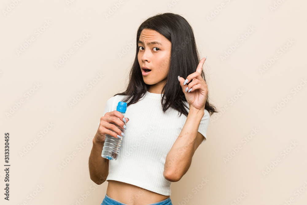 Young asian woman holding a water bottle having some great idea, concept of creativity. Young asian woman holding a water bottle having some great idea, concept of creativity.